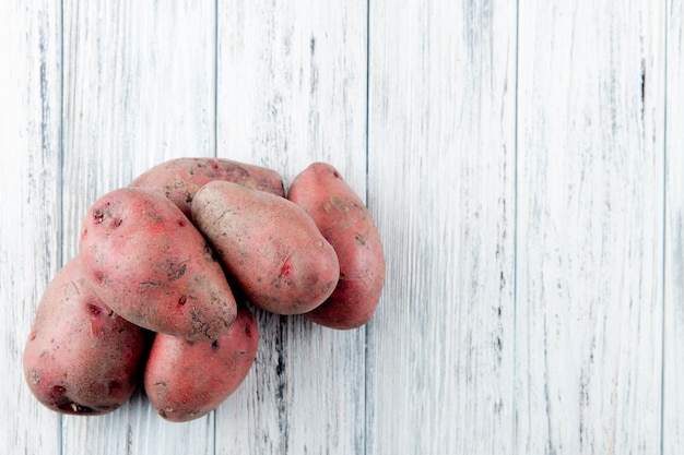 Close up view of potatoes on left side and wooden background with copy space