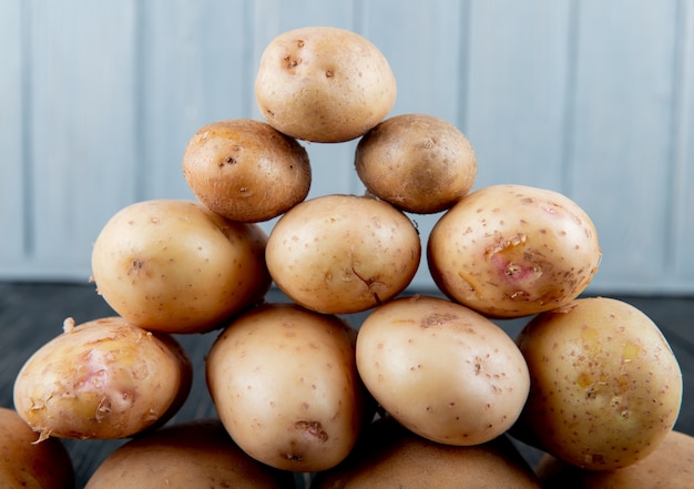 Free photo close up view of potatoes set in pyramid shape on wooden surface and background with copy space