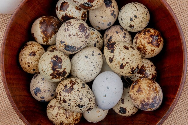 Close up view of quail eggs on a wooden bowl on sack cloth background