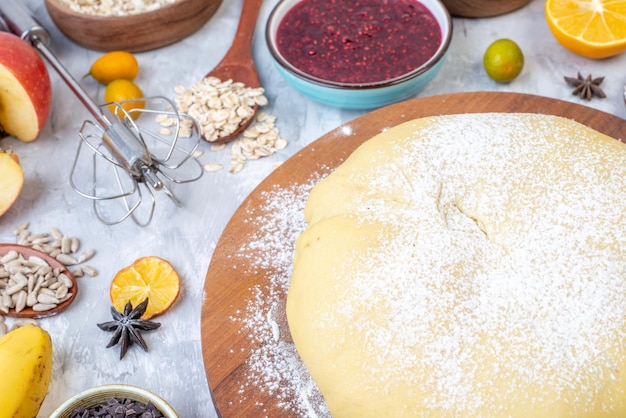 Close up view of raw pastry flour on round board jam banana eggs kumquats oatmeal on gray background