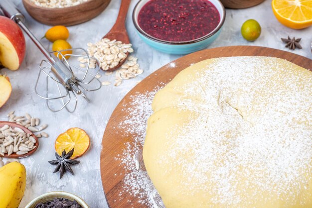 Close up view of raw pastry flour on round board jam banana eggs kumquats oatmeal on gray background