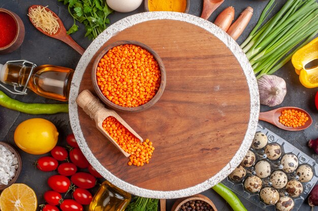 Close up view of red lentil in a brown pot on cutting board among organic vegetables