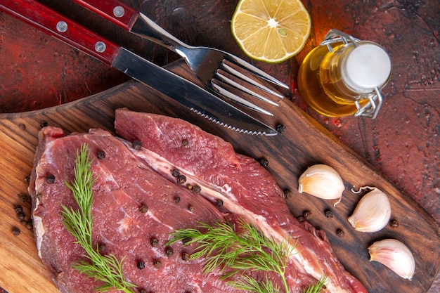 Close up view of red meat on wooden cutting board and garlic green pepper oi bottle for and knife on dark background stock image