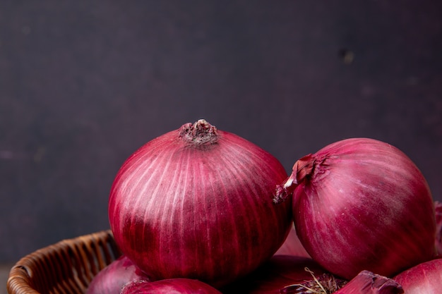 Close-up view of red onions on maroon background with copy space