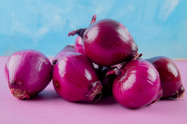Close-up view of red onions on purple surface and blue background with copy space