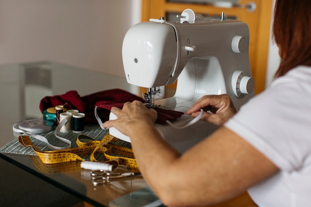 Vista del primo piano delle mani di una donna senior che cucono le maschere di protezione