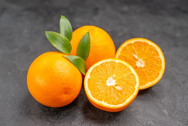 Close up view of set of yellow whole and chopped oranges on dark table