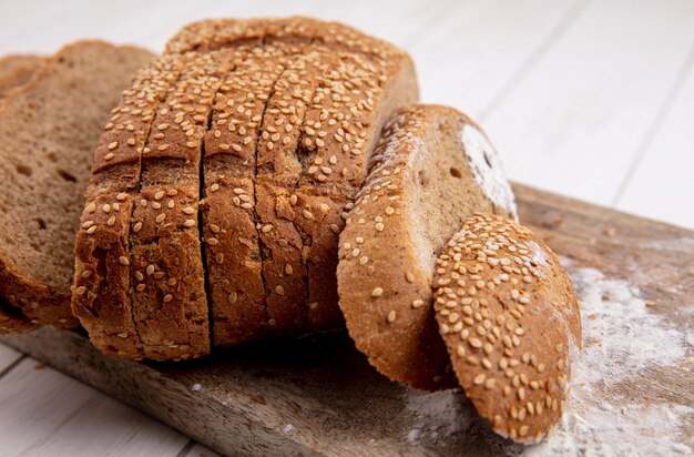 Close-up view of sliced brown seeded cob on cutting board on wooden background