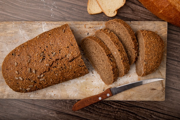 Close-up view of sliced and cut sandwich bread with knife on cutting board on wooden background