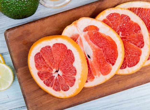 Close-up view of sliced grapefruit on cutting board on wooden background