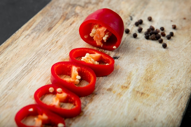 Close-up view of sliced pepper with pepper spice on wooden surface with copy space