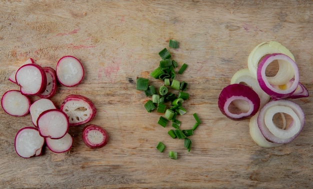 Free photo close-up view of sliced vegetables as radish scallion and onion on wooden background