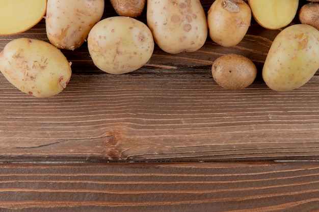 Close up view of sliced and whole potato on wooden background with copy space