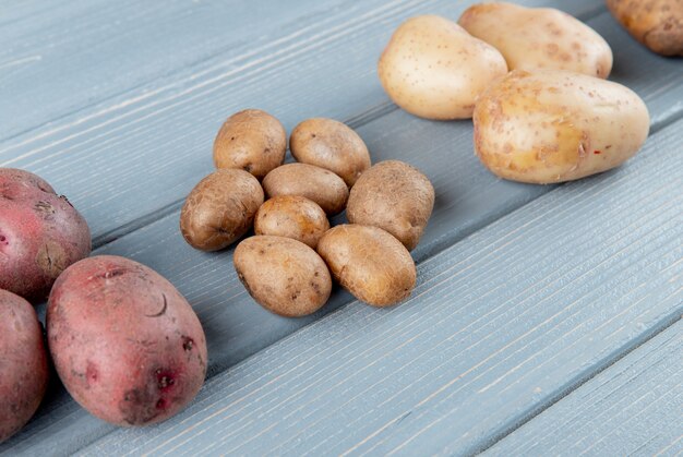 Close up view of small potatoes with big ones on wooden background with copy space