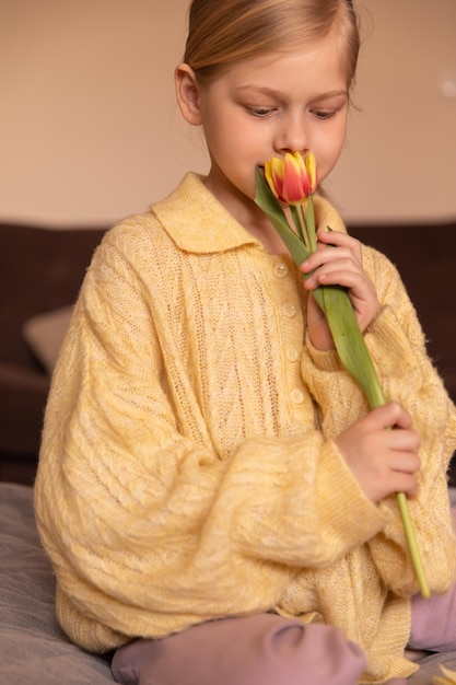 Close up view of smiling cute young child at home smell flowers