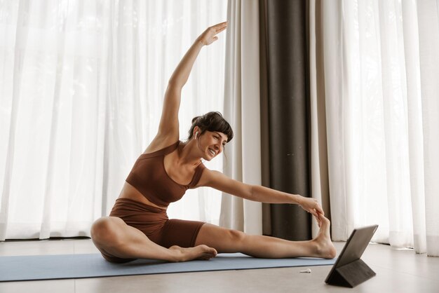 Close up view of smiling woman doing stretching exercise on laptop