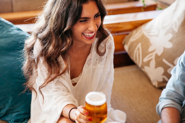 맥주와 함께 웃는 여자의 볼을 닫습니다
