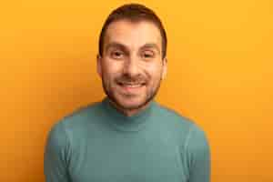 Free photo close-up view of smiling young caucasian man looking at camera isolated on orange background