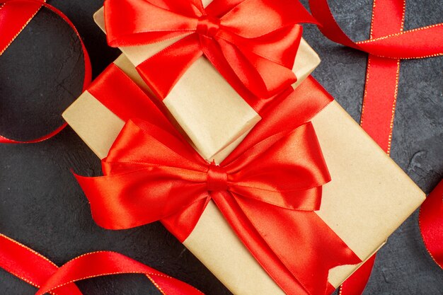 Крупным планом вид уложенных красивых подарков с красной лентой на темном фоне