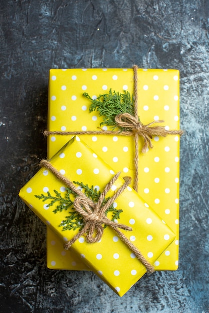 Close up view of stacked beautiful yellow Christmas gift boxes for family member on dark background