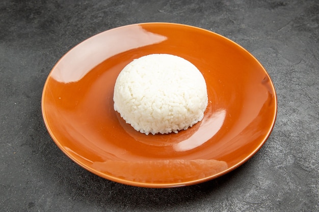 Close up view of steamed rice meal on a brown plate on dark