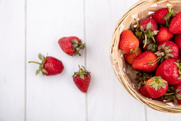 Close up view of strawberries in basket and on wooden surface