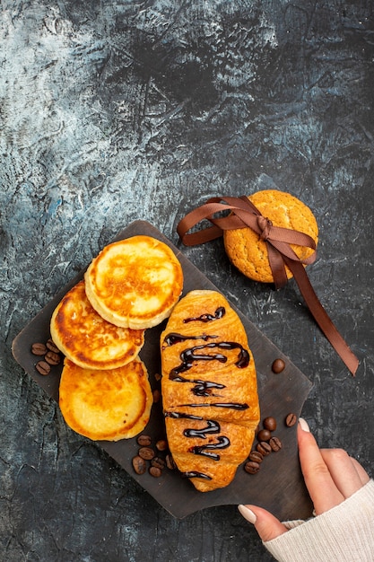 Close up view of tasty breakfast with pancakes croisasant stacked cookies on dark surface