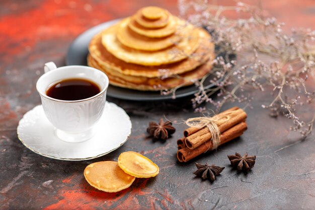 Крупным планом вид вкусного завтрака с пышными блинами и чашкой чая рядом с корицей и лаймом