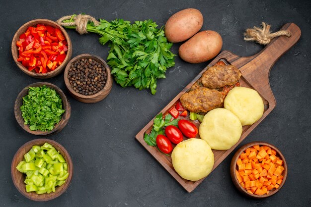 Close up view of tasty cutlets with vegetables and a bunch of green on dark