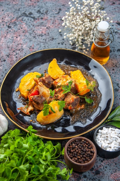 Foto gratuita vista ravvicinata di una gustosa cena con patate a base di carne servito con verde in una bottiglia di olio di aglio nero e spezie