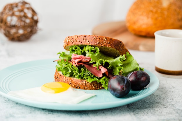 Close-up view of tasty sandwich next to plums