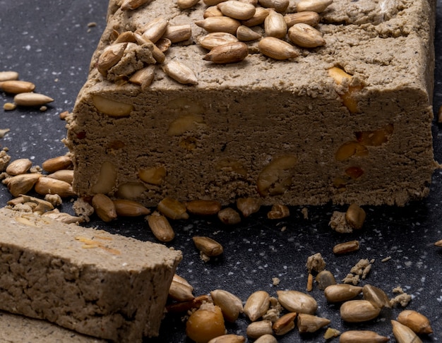 Close up view of tasty slices of halva with sunflower seeds on a black board