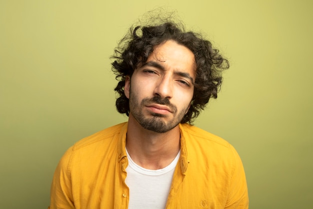 Close-up view of thoughtful young handsome caucasian man  isolated on olive green wall