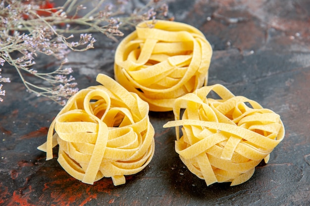 Close up view of three portions of uncooked spaghetti on mixed color table