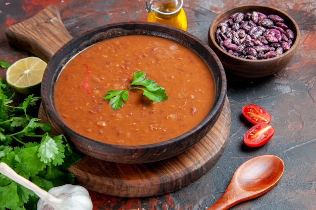 Close up view of tomato soup and beans on a cutting board on a mixed color table