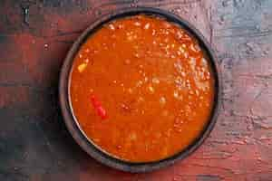 Free photo close up view of tomato soup in a brown bowl on mixed color table