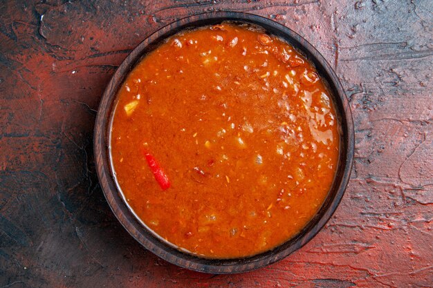 Крупным планом вид томатного супа в коричневой миске на столе смешанных цветов
