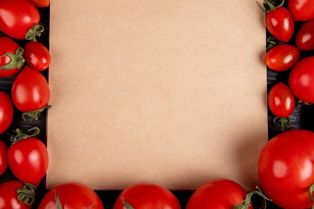 Close-up view of tomatoes around note pad on wooden table with copy space