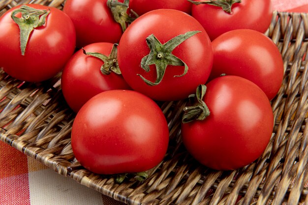 Close-up view of tomatoes in basket plate on plaid cloth