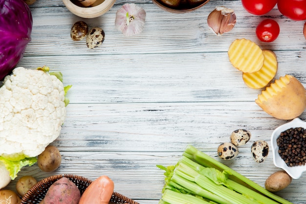 Close up view of vegetables as cauliflower potato egg garlic celery tomato with black pepper on wooden background with copy space