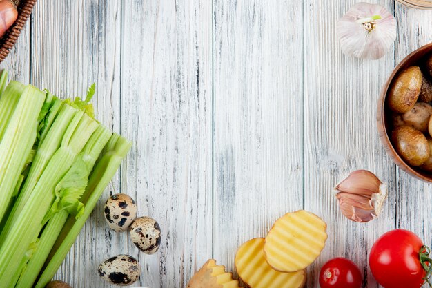 Close up view of vegetables as celery egg potato garlic tomato on wooden background with copy space