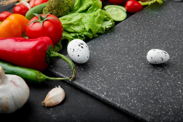 Close-up view of vegetables as egg pepper tomato and others with cutting board