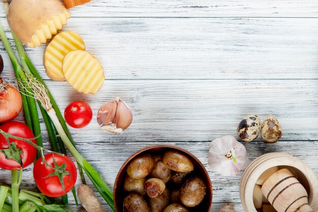 Close up view of vegetables as garlic tomato egg scallion with baked potatoes in bowl on wooden background with copy space