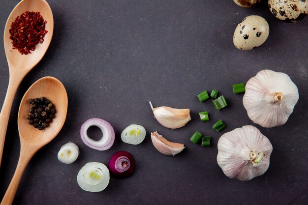 Close-up view of vegetables as onion garlic scallion egg and spices on maroon background with copy space