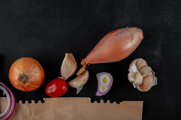 Close-up view of vegetables as onion tomato shallot garlic on black background with copy space
