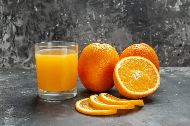Крупным планом вид нарезанного источника витамина и целых свежих апельсинов на сером фоне