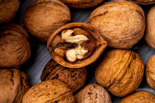 Close up view of walnuts closed and broken scattered on a wooden