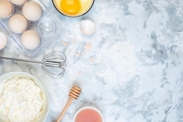 Close up view of white flour in a bowl and stainless cooking tool eggs jam on the right side on two-toned background