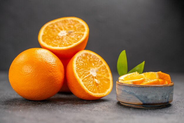 Крупным планом вид целых и нарезанных свежих апельсинов на темном столе