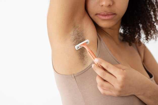 Close-up view of woman removing armpit hair